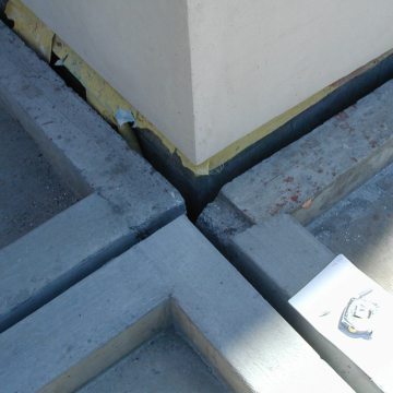 Perimeter expansion joints between the parking deck roof and each building intersect with mid-span structural joints at every building corner. The top deck is a hot-rubberized asphalt-waterproofed split-slab. Continuity of seal through changes in plane and direction, from deck-to-deck to deck-to-wall was a fundamental performance criteria.