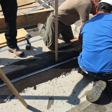 RoofJoint lower flange secured to deck with termination bar and concrete anchors.