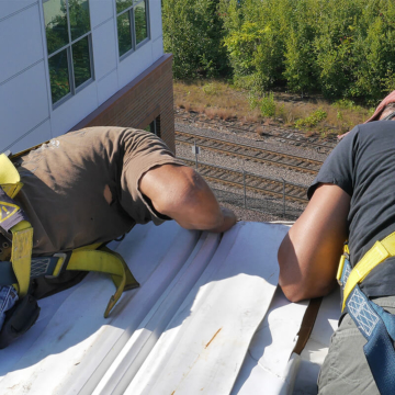 Roofing contractor installing a RoofJoint roof to wall transition - Emseal