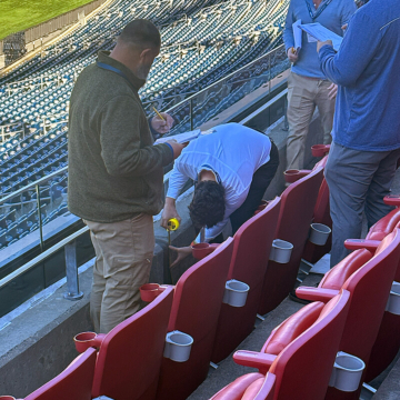 Sika Emseal technical and engineering team measuring stadium expansion joint widths at stair tread and riser transitions to assess building movement requirements in a seating area.
