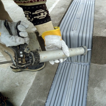 Applying epoxy sealant band to SJS seismic expansion joint system during install at Basra International Stadium