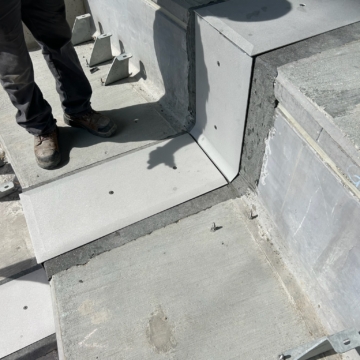Close-up of a custom coverplate at a tread-riser transition at Ryan Field, showing the upturn detail carrying the seal over the chamfer where the riser meets the tread.
