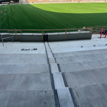 Expansion joint running from the playing field wall through the seating bowl steps at Ryan Field, showing the joint's continuous path across the transition from field level to the tread-and-riser stairway.