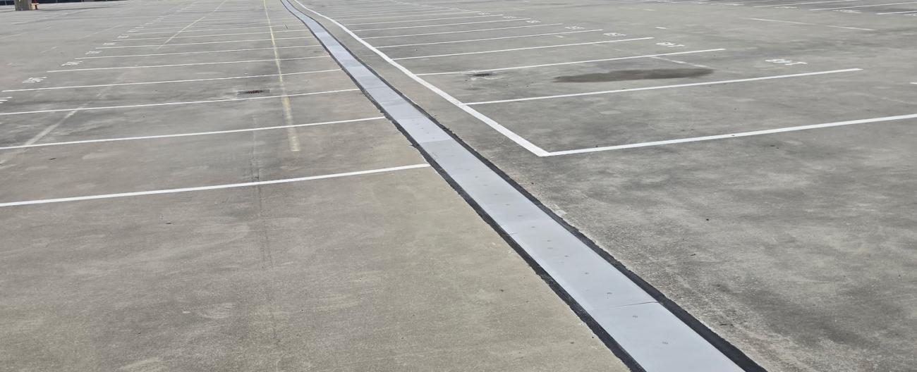 Vue d'ensemble du système de joints de dilatation SJS traversant le parking du centre de location de voitures de l'aéroport d'Atlanta, avec le terminal en arrière-plan.