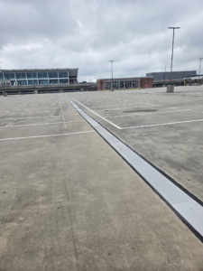Vue d'ensemble du système de joints de dilatation SJS traversant le parking du centre de location de voitures de l'aéroport d'Atlanta, avec le terminal en arrière-plan.